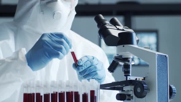 Scientist in protection suit and masks working in research lab using laboratory equipment.