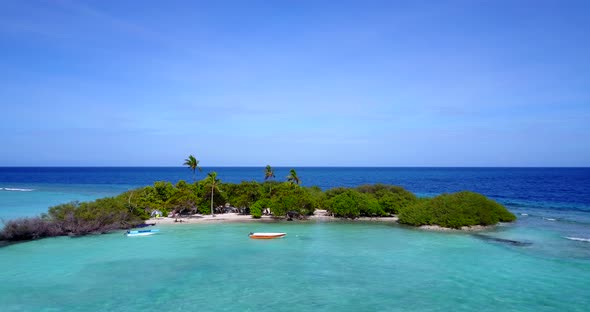 Daytime above tourism shot of a sandy white paradise beach and aqua blue ocean background in vibrant