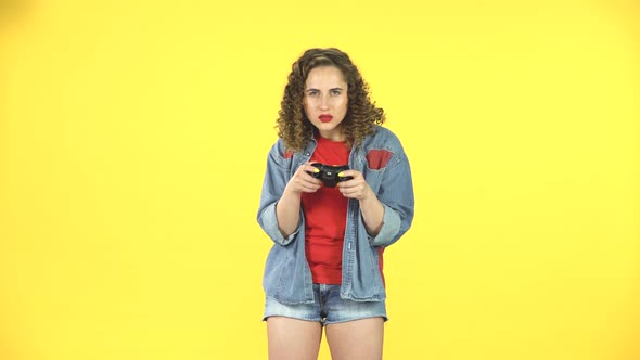 Girl Playing a Video Game Using a Wireless Controller on Yellow Background