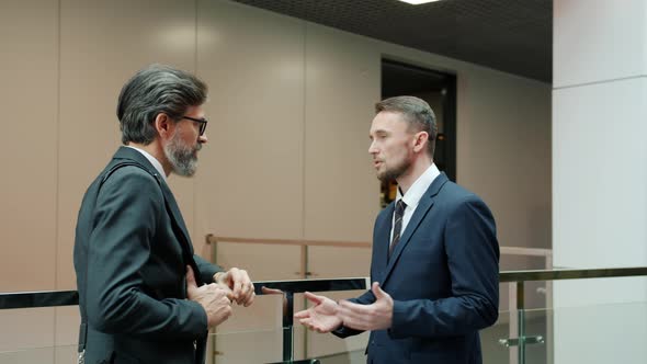 Business Partners Elegant Men in Formalwear Discussing Work in Office Lobby