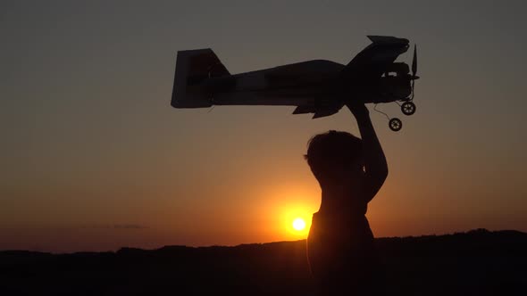 Boy with A Wooden Plane Against the Sunset.