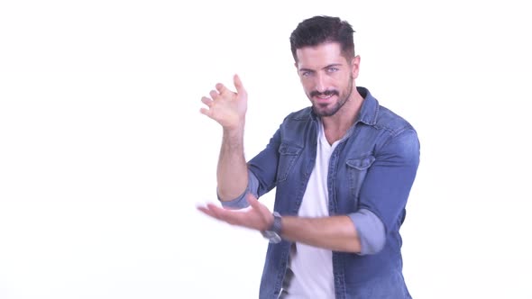 Happy Young Bearded Hipster Man Snapping Fingers and Showing Something