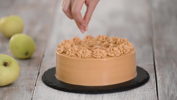 Pastry Chef Sprinkles of Almond Flakes on a Caramel Cake