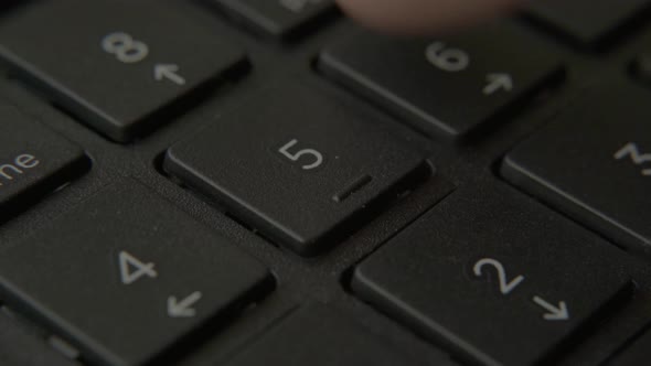 The Finger Presses a Button with a Number on the Keyboard