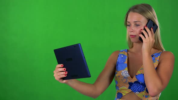 Young Pretty Blond Woman Works on Tablet and Phone with Smartphone - Green Screen - Studio