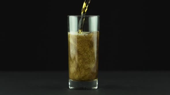 Cola Is Poured Into Glass Full of Bubbles and Foam Isolated on Black Background