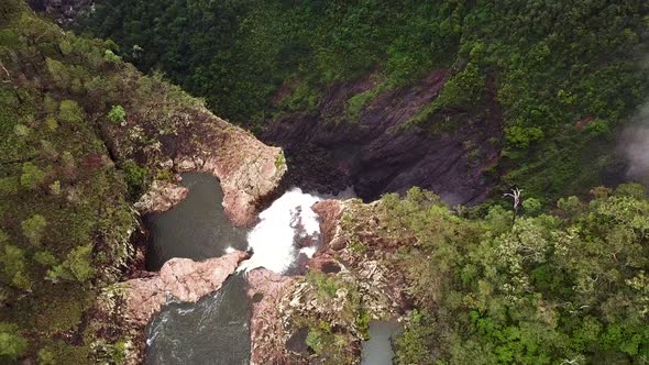 Drone flys over cliff edge revealing massive waterfall.