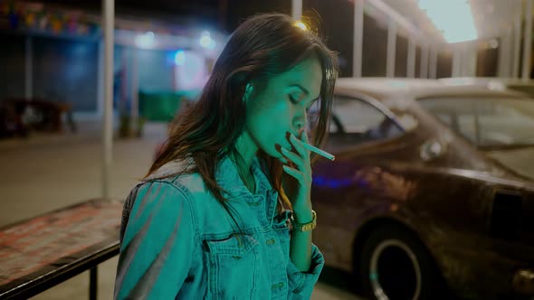 A Girl Smokes in Front of a Rusty Classic Car While Typing a Message Late at Night