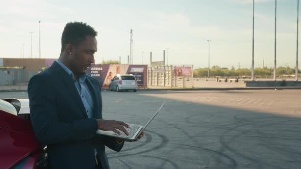 Businessman Talking on Laptop with Friend When Own Luxurious Electromobile