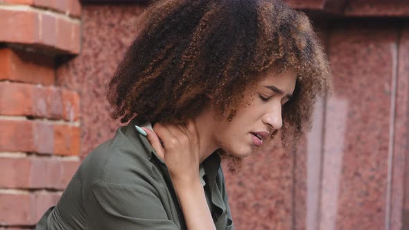 Closeup View African American Woman Siting Outdoor Experiences Severe Pain in Neck Rubbing It to