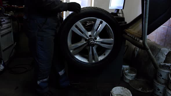 Balancing car wheel on profissional machine equipment by professional mechanic at servise station