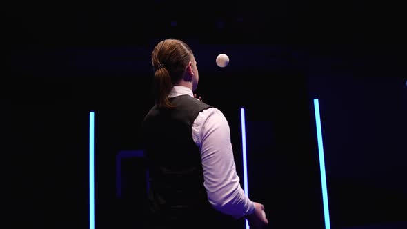 Circle Movement Camera Around Professional Circus Performer Juggling White Balls Against a Black