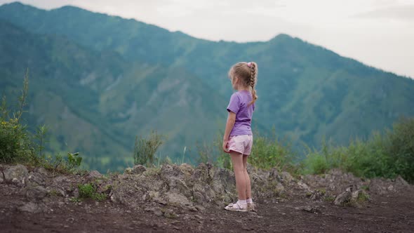 Thoughtful Little Girl Looks at Old Mountain Silhouettes