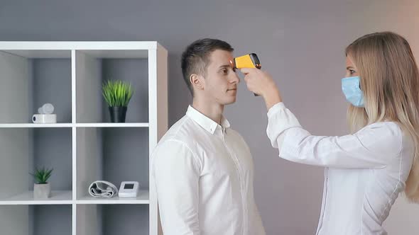 Doctor Measures the Patient's Temperature with a Non-contact Infrared Thermometer, Patient's Visit