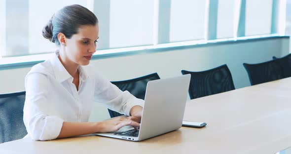 Cheerful executive using laptop in conference room