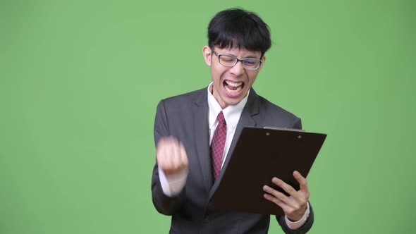 Young Happy Asian Businessman Reading Clipboard and Getting Good News