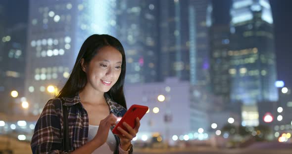 Woman work on mobile phone in city at night