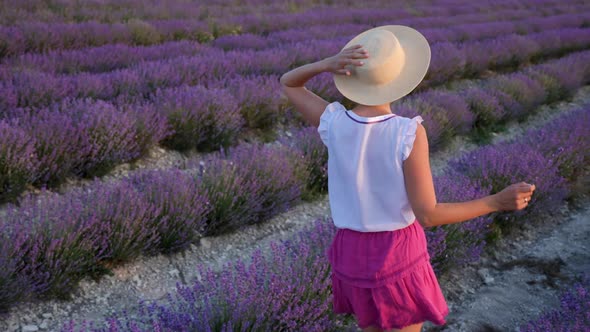 Woman in a Short Purple Dress and a Hat Stands on a Lavender Field