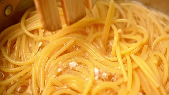 Raw spaghetti is being cooked in boiling water in a kitchen pot.