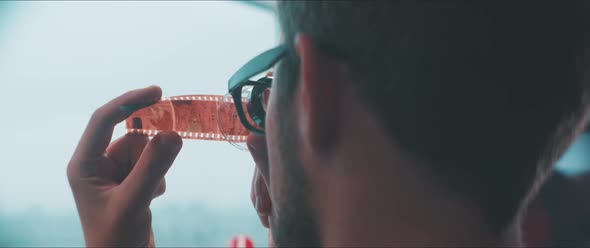 Young Man examines filmstrip, Woman in the background