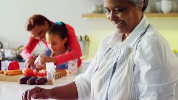 Smiling grandmother holding recipe book in kitchen 4k