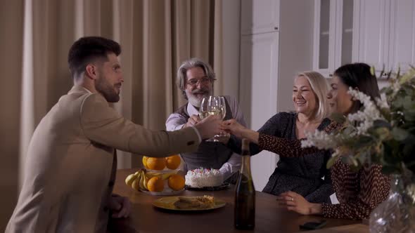 Happy Family Sitting at Holiday Dinner in Kitchen and Drinking Champagne