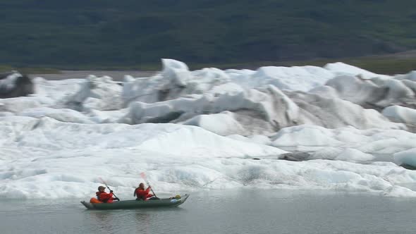 Couple kayaking by icebergs and glacier, Alaska