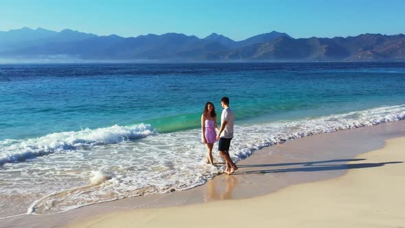 Two people happy together on tropical coastline beach break by blue ocean with white sandy backgroun