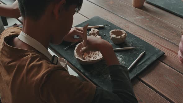 Boy Carving Pattern on Bowl of Clay