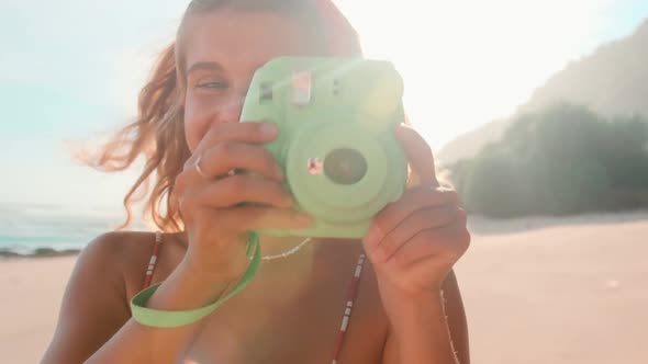 Young Caucasian Woman Cute Smiling Takes Picture on Funny Camera Stands on Beach