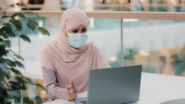 Young Arab Woman in Hijab Wearing Protective Mask Reading Email on Laptop Receiving Bad News Girl