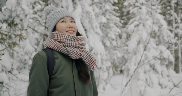 Slow Motion of Beautiful Asian Woman Having Fun with Snow Outdoors in Winter Woods
