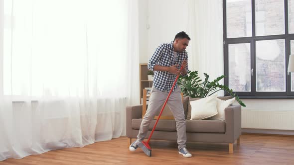 Man with Broom Cleaning and Having Fun at Home