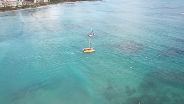 4k aerial drone shot as sunset dinner cruise boats take couples out past the surf line to enjoy drin