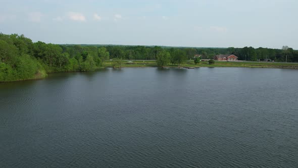 A drone shot of a beautiful lake in summer time with it's green surroundings