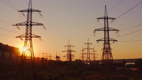 High-voltage power towers. The dark silhouette of towers in the rays of the beautiful evening sun. 