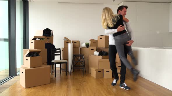 A Happy Moving Couple Is Excited About Moving Into a New Apartment, Hugs and Spins Around