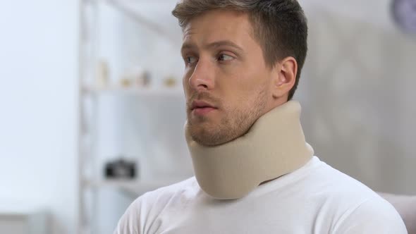 Upset Man in Foam Cervical Collar Suffering From Neck Discomfort, Rehabilitation