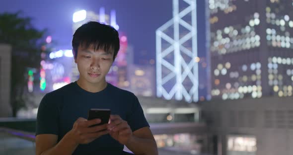 Man use of mobile phone in Hong Kong city at night