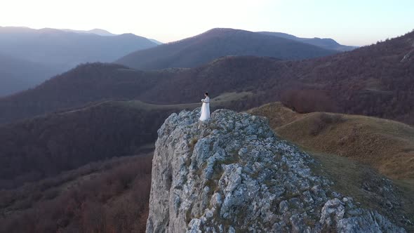 Aerial Drone Wedding Shot of a Bride in White Dress Standing on a  Mountain Peak