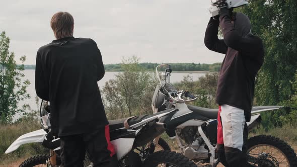 Men Resting by Lake after Riding Motorcycles