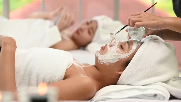 Beautiful Asian woman enjoying applying white mud to her face. at a luxury spa resort