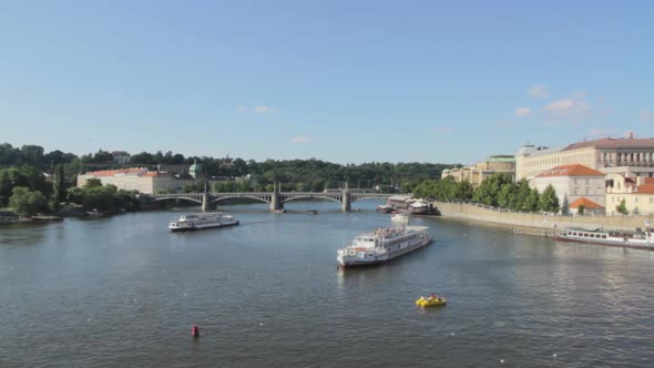 Beautiful shot of a river in Prague at daytime with ships sailing across the river.