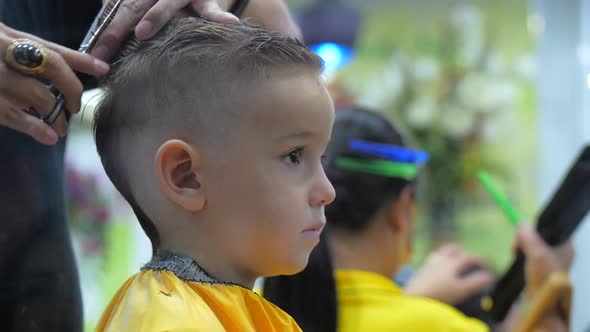 Children's Haircut in the Salon at the Time of the Coronavirus Epidemic. Little Boy Gets a Haircut