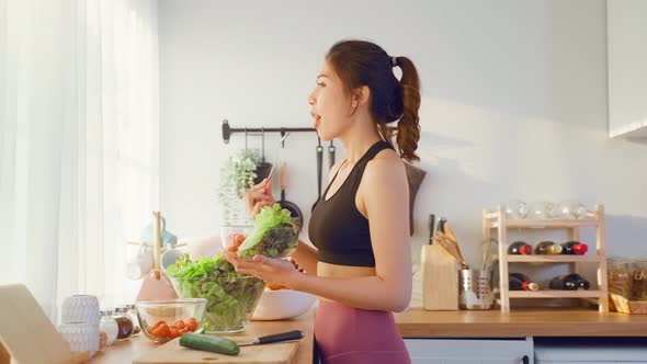 Asian attractive sport woman holding salad bowl and eat vegetables.