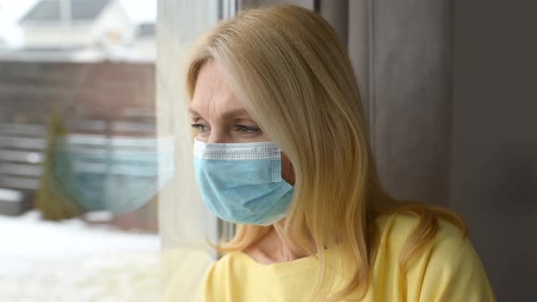 Mature Lady in Protective Face Mask Looking at the Window and Feeling Sad