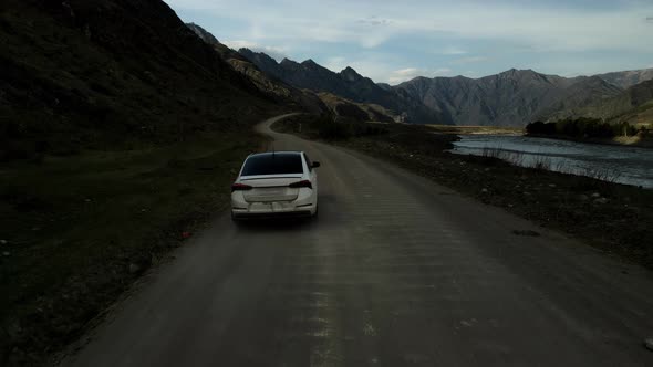 A White Car Moves Through a Mountainous Area