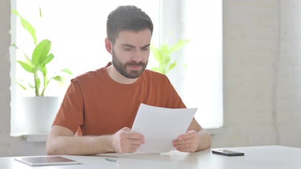 Upset Young Man Reacting to Loss on Documents