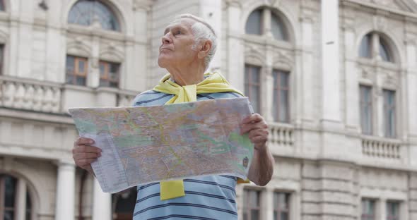 Senior Male Tourist Exploring Town with a Map in Hands and Looking for the Route