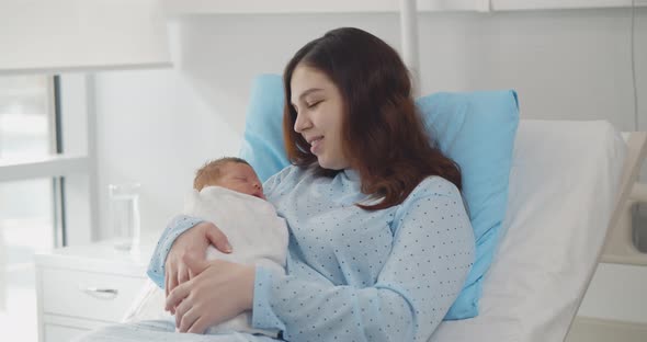 Mother Rest with Newborn Baby in Bed After Natural Birth Labor